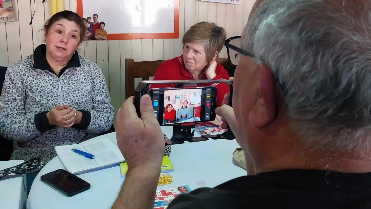 Participante del taller grabando con su celular una entrevista a dos vecinas